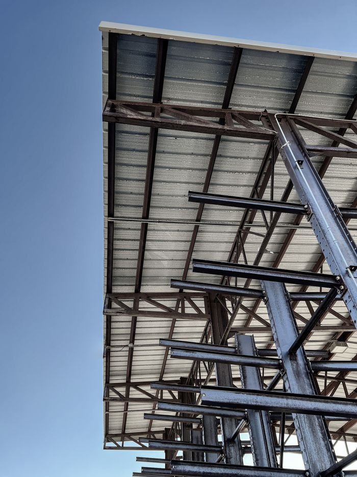 An industrial steel structure under construction against a clear blue sky, showcasing architectural design.