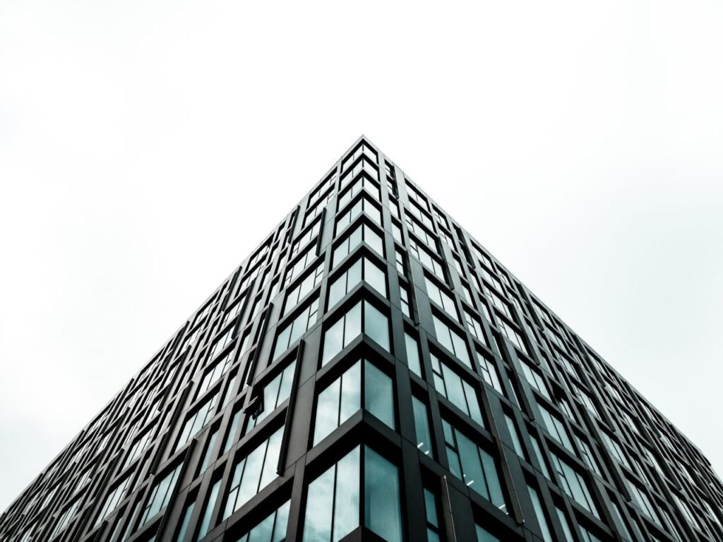 Low angle view of a modern high-rise building with geometric patterns against a white sky.