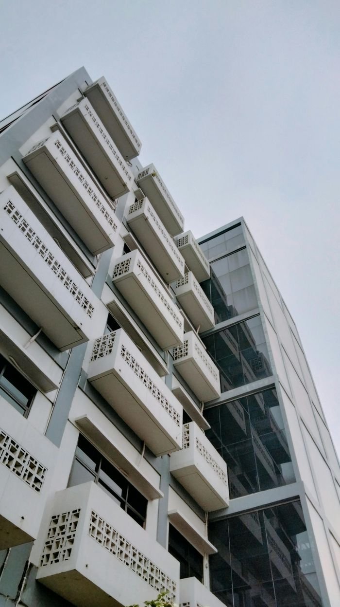 A modern building exterior with distinctive balcony designs and glass façade, shot from below.